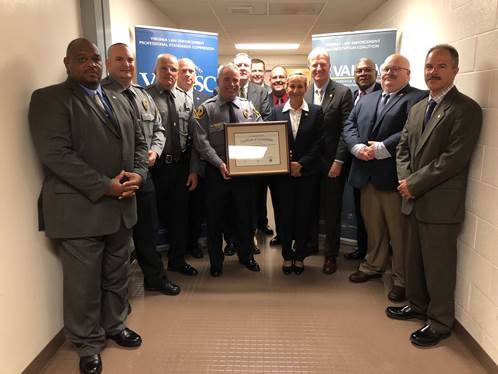 The entire UMW Police Department holding a framed accredidation document.