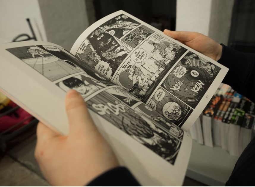 A person holds open a thick comic book.
