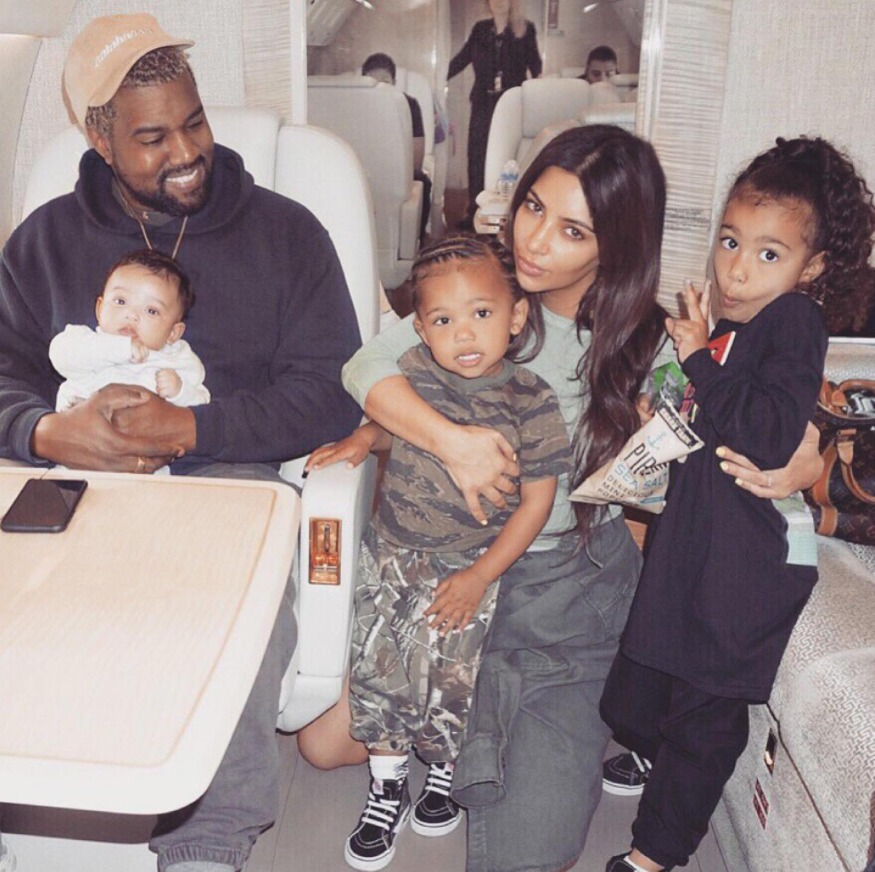 Kim Kardashian and Ye pose for a picture on a plane with their three children.
