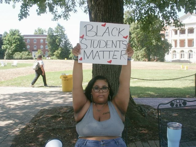A woman holds a sign that says "BLACK STUDENTS MATTER."