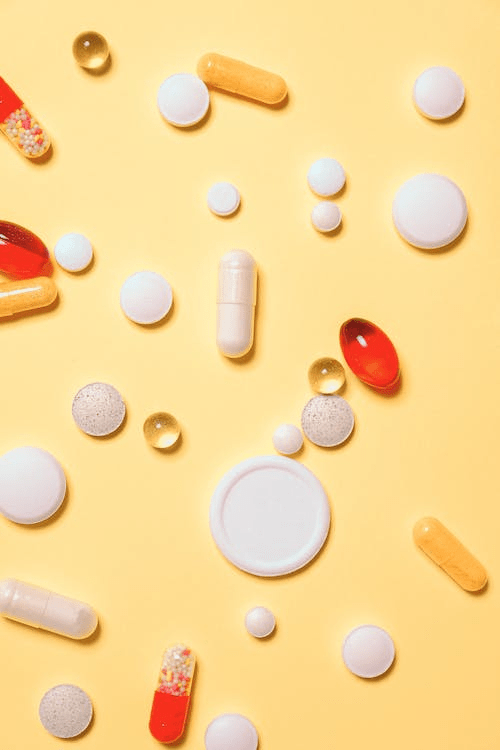 various shapes and sizes of pills scattered across a yellow background