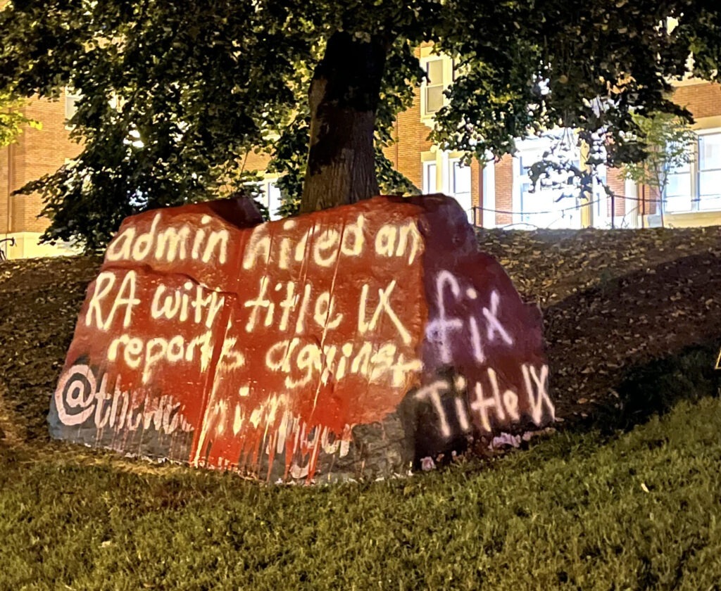 The Spirit Rock is painted red. dripping over where it was previously painted black. It reads "admin hired an RA with title IX reports against him" and "fix Title IX."