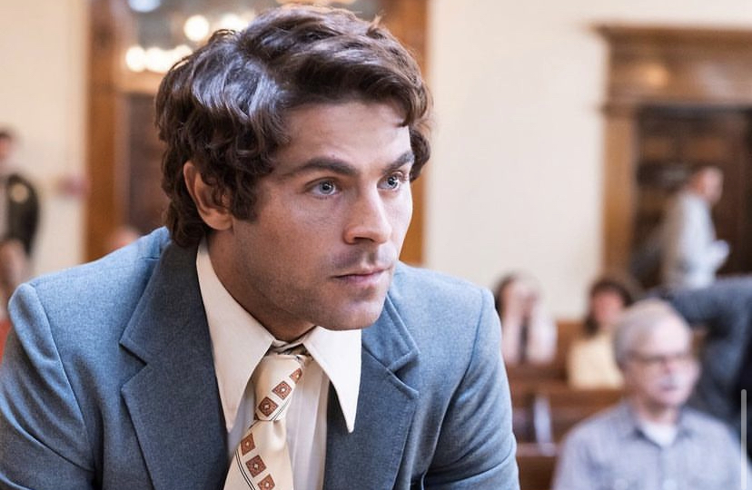 Zac Efron as Ted Bundy in a suit in a courtroom.