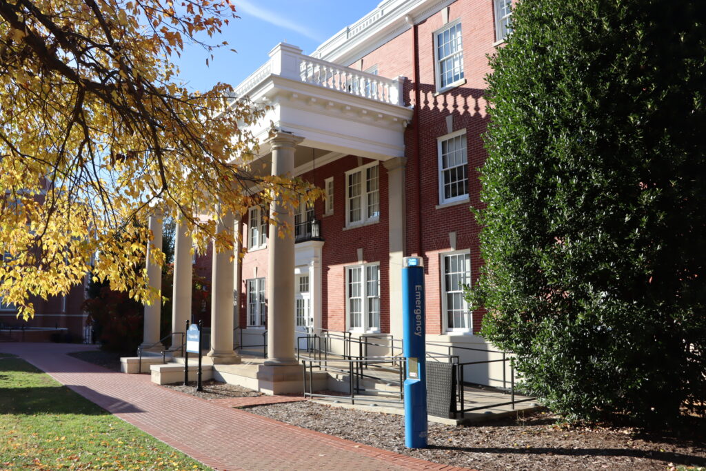 A picture of virginia hall from the side. It is an old brick building with while columns