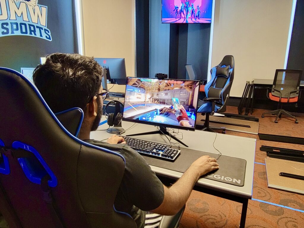Male college student playing video games on computer.