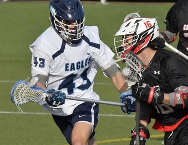 Male lacrosse player defends against other player.