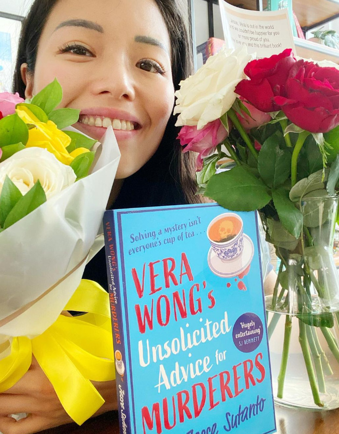 A woman's face centered between two bouquets of flowers and the book centered under her chin titled "Vera Wong's Unsolicited Advice for Murderers."