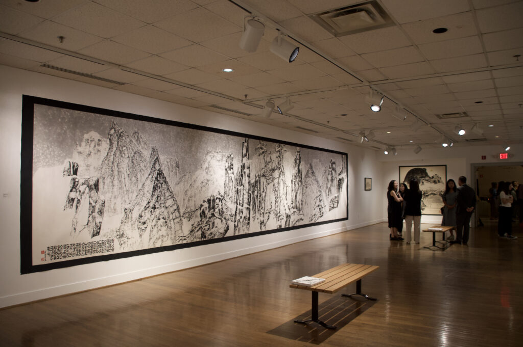 Ink painting in a gallery display with high mountains heavily detailed and textured.