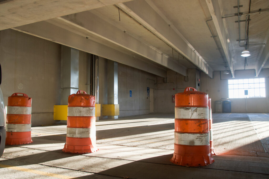 Orange and white cones are placed in a straight line on the fourth floor of the Eagle Landing Parking Deck.