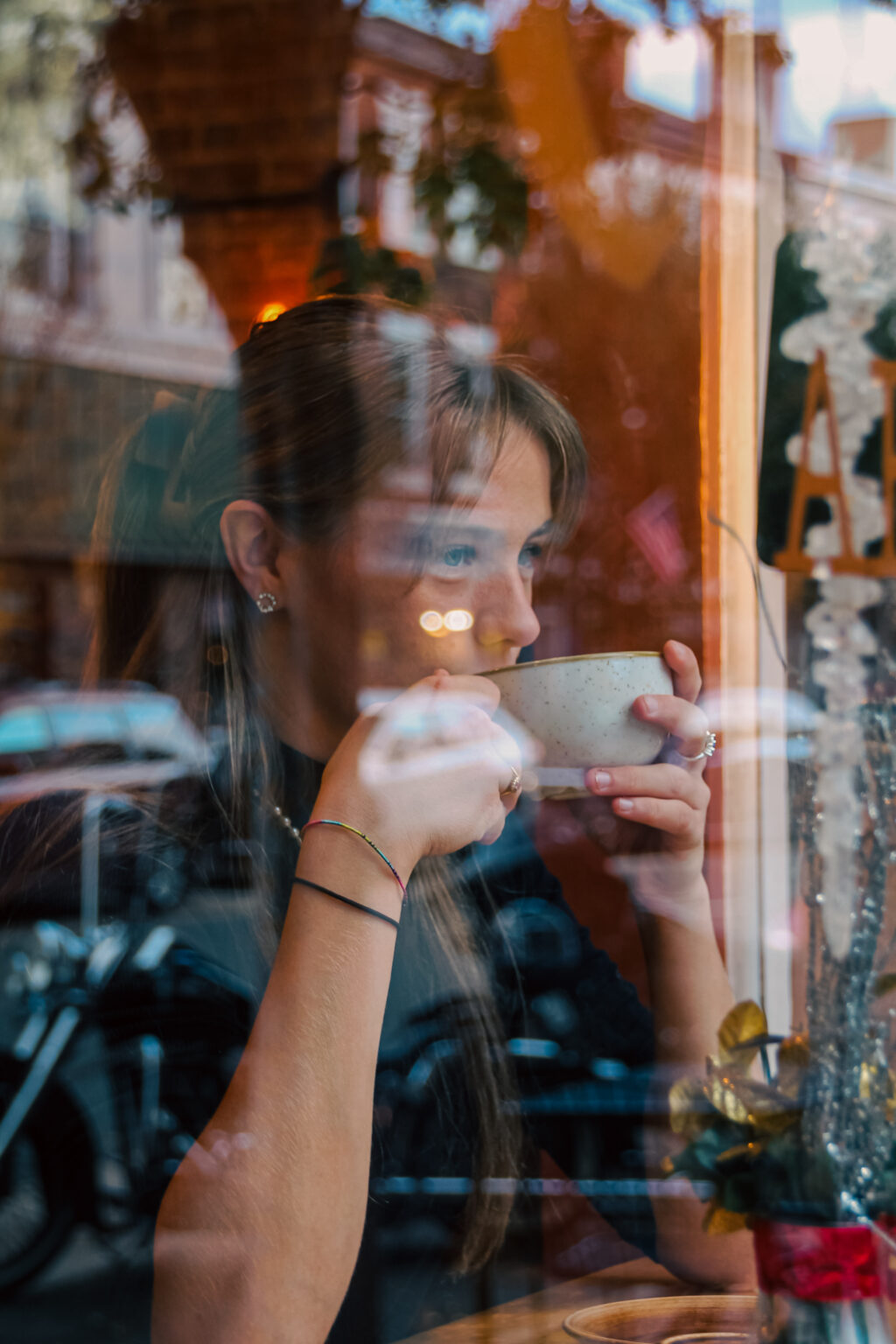 A women drinking a cup of coffee through a glass window
