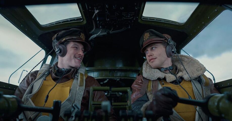 Two pilots in leather jackets in what appears to be a military aircraft from WWII.
