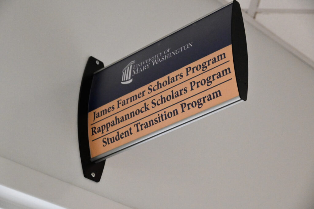 A blue and yellow sign listing the James Farmer Scholars Program, Rappahannock Scholars Program, and Student Transition Program.