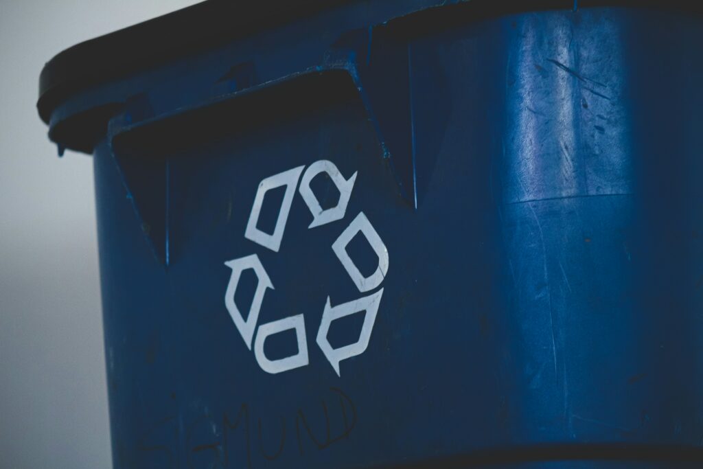 A blue trash bin with a recycling sign