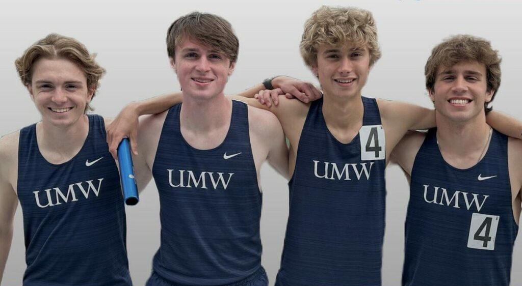 Four UMW men track and field runners stand side by side with arms around each other. They are wearing navy blue track uniforms that say, "UMW."