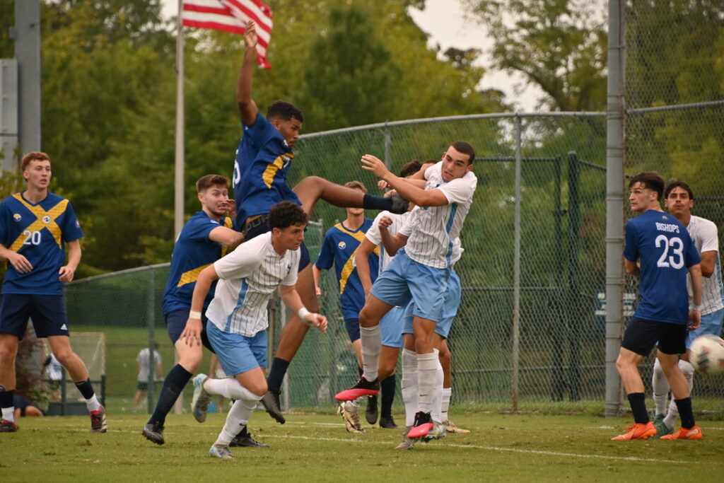 A group of men playing soccer fight over the ball.