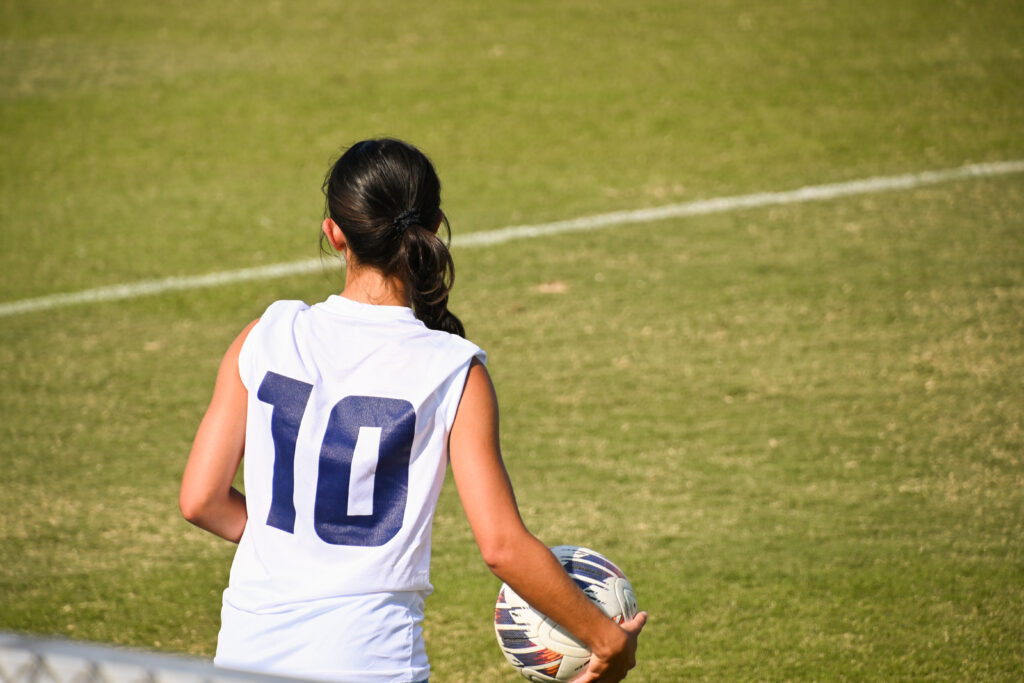 A University of Mary Washington player, weaning number 10, prepares to throw in a soccer ball from the side of the pitch with her back to the camera