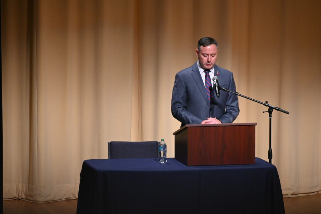 Eugene Vindman stands at a podium next to a microphone amidst a political debate.