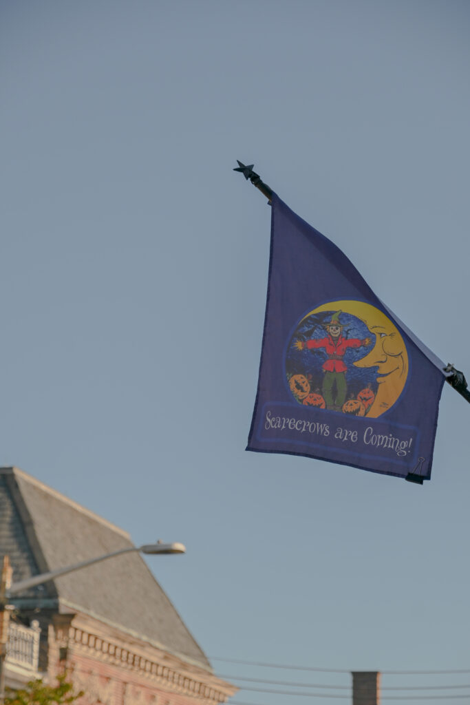 An image of a flag flying that says "Scarecrows are coming" with a picture of a scarecrow and a crescent moon.