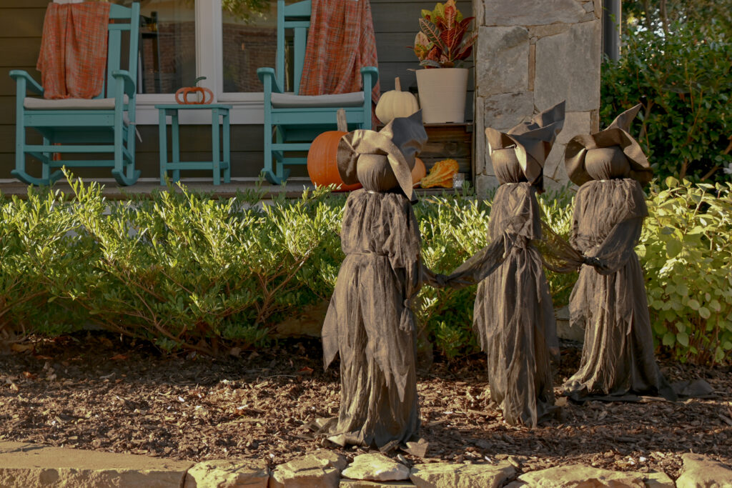 An image of three fake black witches decorate somebody's front yard.