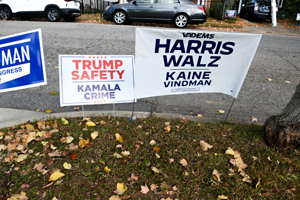 Three different yard signs erected in a row, two of which endorse Republican candidates, and one which endorses Democratic candidates.