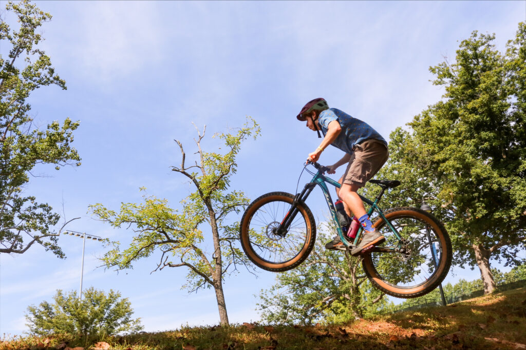 Bike rider soars over a hill on a local bike path.